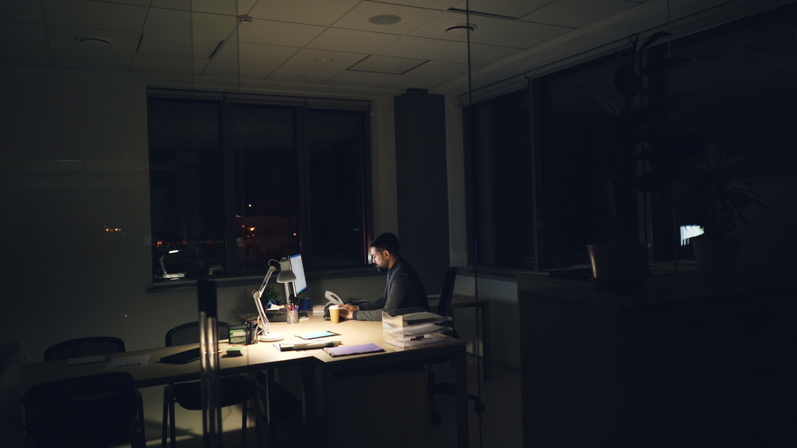 Developer working late in a dark office lit by a desk lamp