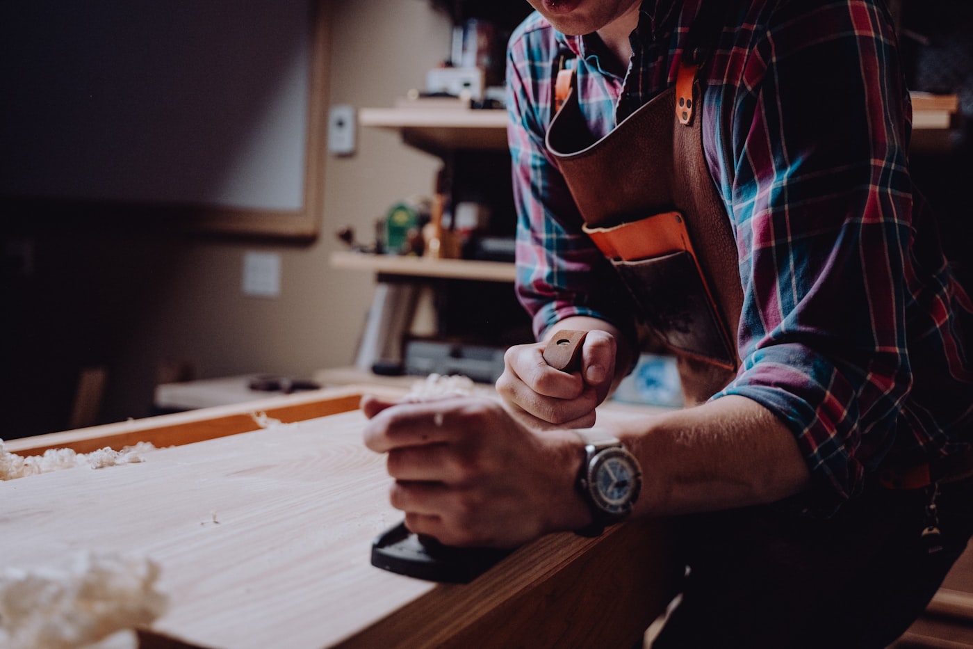 Carpenter hand-planing timber at a workshop bench
